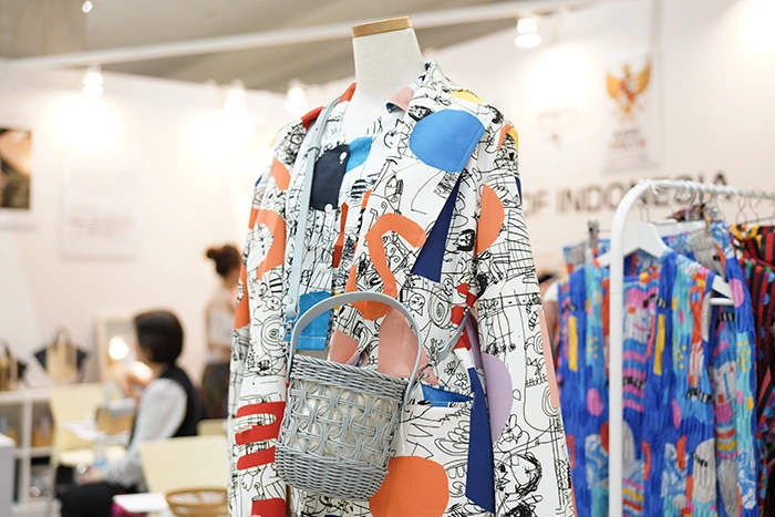 A vibrant, patterned jacket paired with a woven basket-style bag showcases a creative blend of bold prints and unique accessories, reflecting contemporary fashion’s fusion of art and design.