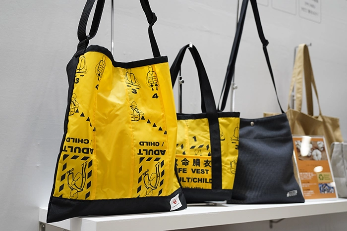 Tote bags repurposed from vintage safety vest materials, showcase innovative circular design at FaW TOKYO, blending sustainability with style and functionality.