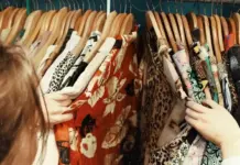 UK Resale Accelerates as Cost Pressures Shift Fashion Demand People browsing through a rack of colorful patterned dresses on hangers.