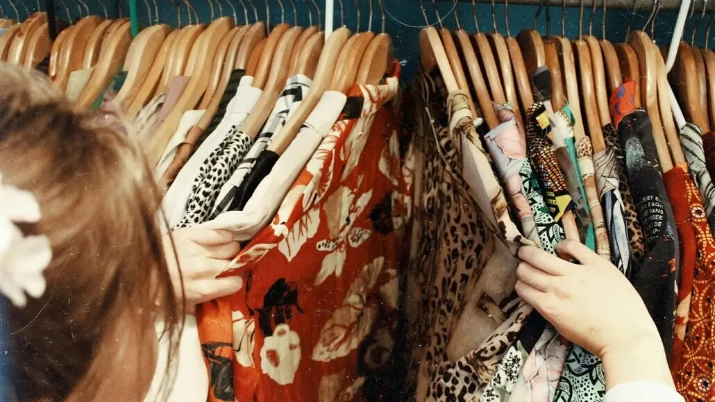People browsing through a rack of colorful patterned dresses on hangers.