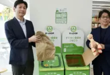 FamilyMart Japan Initiatives Address Textile Waste Through Reuse and Recycling Two men in suits stand beside a green R-LOOP recycling station, each holding recyclable items.