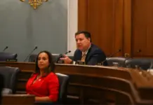 Lawmakers Urge DHS to Tighten US Textile Customs Enforcement Two officials sit at a curved wooden committee desk; a man in a suit speaks into a microphone while a woman in a red blazer looks on.