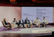 Hyosung TNC Accelerates Sustainable Textile Future with Integrated Bio-Spandex Platform Panel discussion on a stage with six people seated in white chairs, moderator on the left, and a large screen displaying speakers' names in the background.