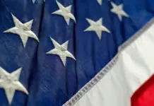US Textile Industry Hails Congressional Push for Stronger Customs Enforcement Against Fraud Close-up of white stars on the blue canton of the American flag with red and white stripes visible.