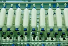 Proposed Duty Hike on Polyester May Slow Bangladeshโs MMF Transition Row of white cylindrical spools with blue ends mounted in an industrial textile/fiber processing machine.