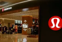 Lululemon Cuts FY26 Outlook as Americas Revenue Slips Lululemon storefront in a mall with a large red circular logo on the right wall and clothing displays inside the store.