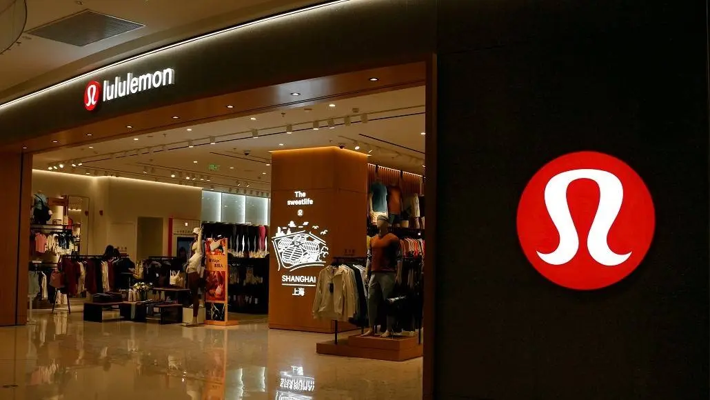 Lululemon storefront in a mall with a large red circular logo on the right wall and clothing displays inside the store.