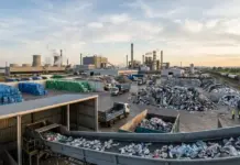 Textile Exchange Publishes New Polyester LCA With Asia Data Wide view of a recycling plant: stacked bales of plastic, trucks, and processing towers in the distance.