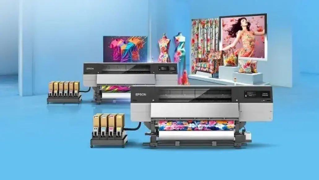 Two Epson large-format printers in a bright blue studio printing colorful fabric‑like designs with ink tanks visible on the side.