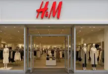 H&M Introduces First Men’s Denim Line Featuring Circ and TENCEL Recycled Fibers H&M storefront with large glass doors, two mannequins in the window displays wearing neutral coats, and shoppers visible inside the clothing store