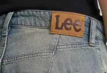 Authentic Brands and Experience Group Team Up to Expand Lee Across Europe Close-up of blue denim jeans waistband with a brown Lee brand patch above the back pocket area.