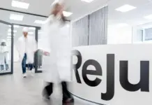 Reju Establishes First U.S. Research and Development Center in Pennsylvania Researchers in white lab coats walk through a bright, modern reception area with a curved desk displaying the word 'Relj' and a small colorful logo.