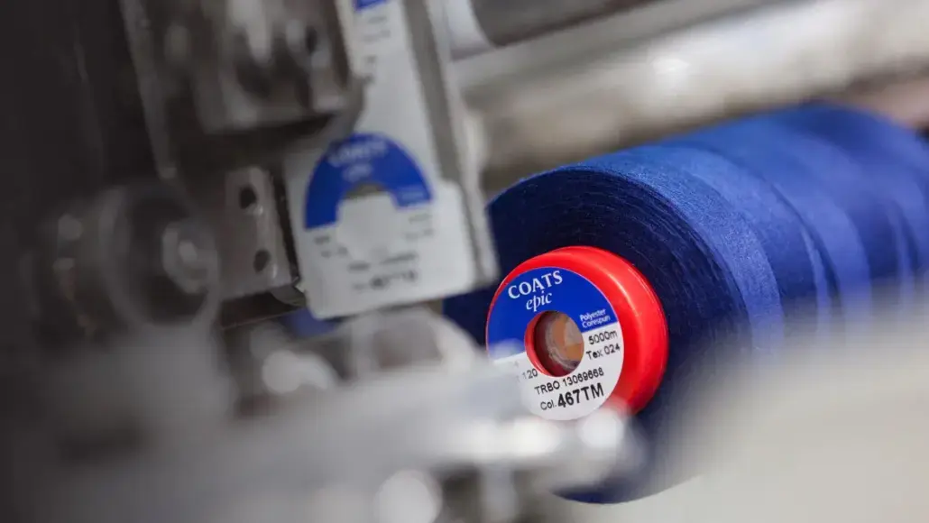 Close-up of a blue COATS Epic thread spool on a sewing machine being wound onto a spindle.