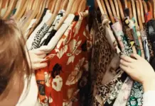 EU Nations Target Ultra-Fast Fashion With Tougher Rules People browsing a clothing rack with colorful patterned dresses on wooden hangers, selecting fabrics with their hands