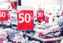 European Union Implements Ban on Disposal of Unsold Clothing and Footwear Clothing store with bright red 50% off signs indicating discounts on apparel stacks and mannequins in background