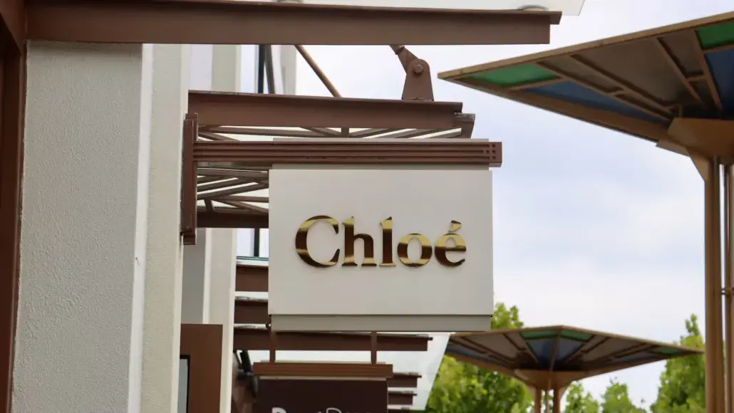 Exterior storefront sign reading 'Chloé' in gold letters on a white panel.