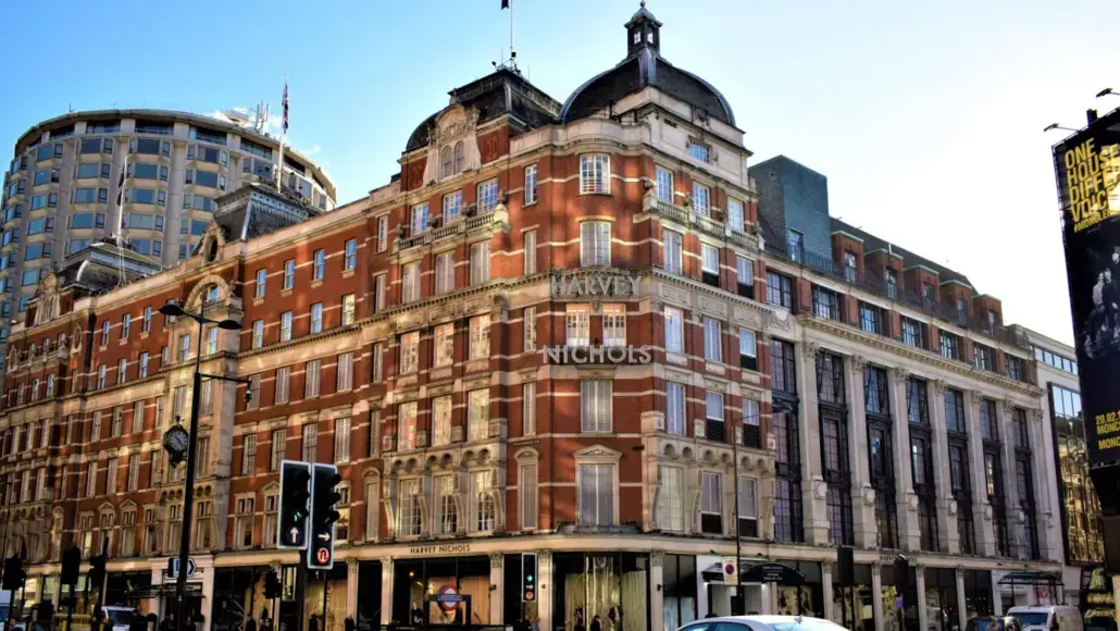 Red brick Harvey Nichols department store on a busy city street with classic arched windows and a curved corner facade in central London/near Piccadilly Circus area