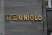 Fast Retailing Reports Record Profits as Global Strategy Reshapes Apparel Industry Golden UNIQLO sign on a gray stone building exterior, with the brand name spelled in large letters and two square logos to the left