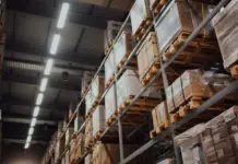 HDE Warns EU Green Claims Rules Could Trigger Product Waste Warehouse aisle with tall metal racks stacked with boxed pallets wrapped in plastic