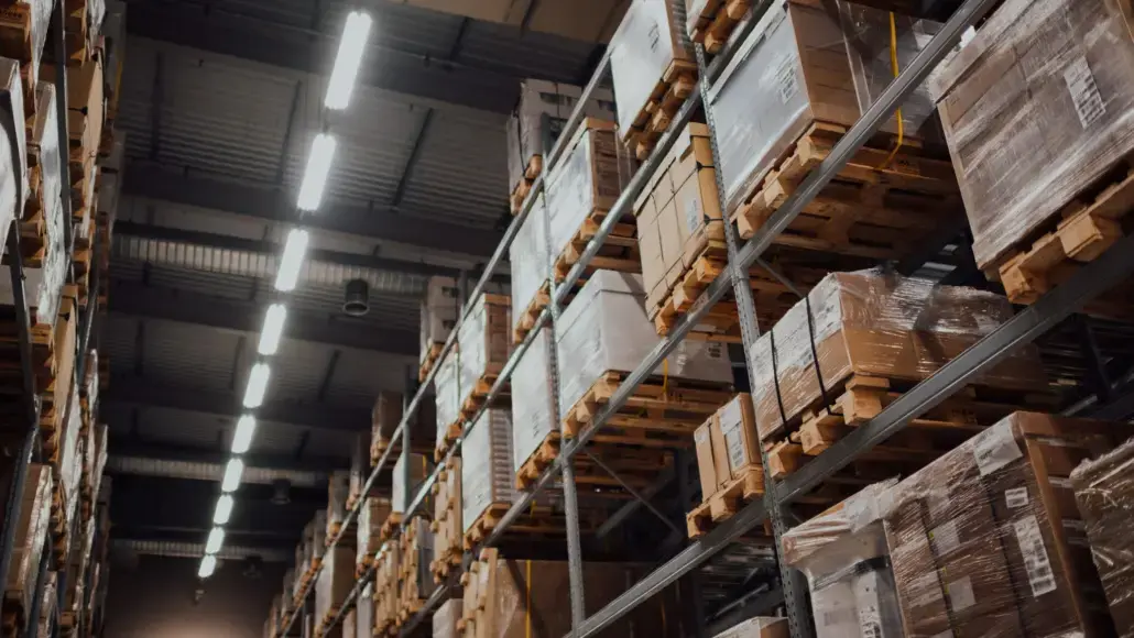 Warehouse aisle with tall metal racks stacked with boxed pallets wrapped in plastic