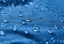Bluesign Enhances Chemical Lists to Align With Stricter PFAS Regulations Close-up of water droplets scattered on a blue textured surface with shallow depth of field.