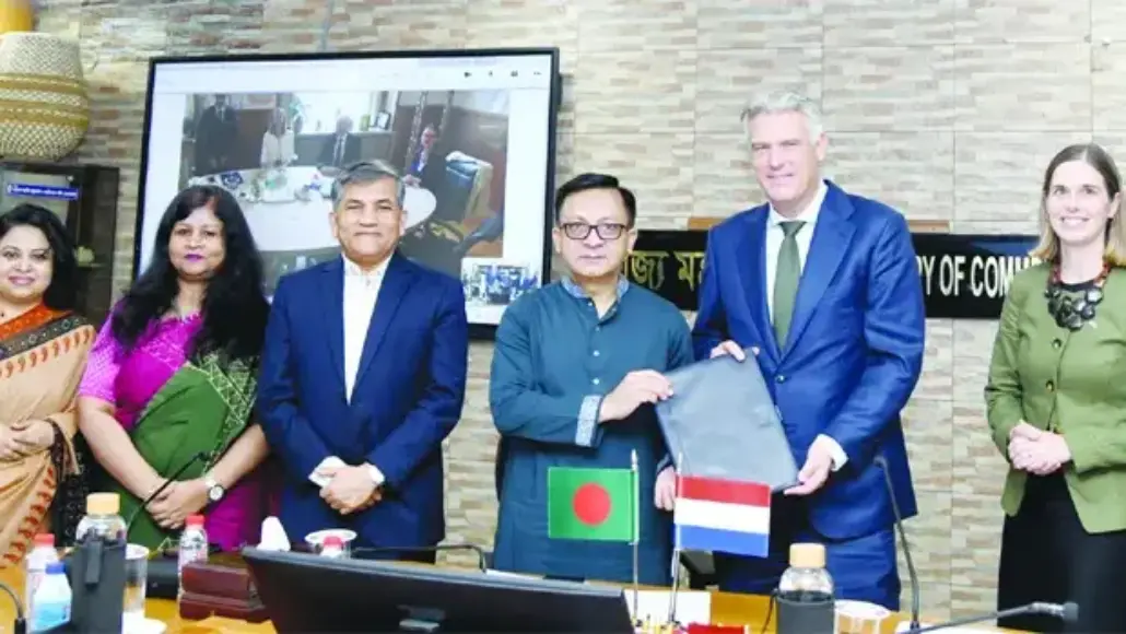 Group of officials at a signing ceremony; Bangladesh and Netherlands flags visible as two men exchange documents.