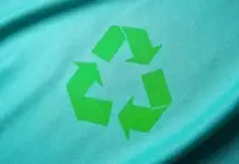 Ellen MacArthur Foundation Joins AMCIRC to Advance Global Circularity Teal fabric with a bright green recycling symbol.