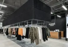 Musinsa Enters Japan’s Recovery-Wear Market as Fashion Meets Wellness Tech Clothing racks with coats in a modern fashion store; a wooden checkout desk and 'MUSINSA HONGDAE' sign in back.