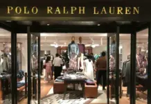 Ralph Lauren Posts Strong Q1 FY27 Results, Raises Annual Outlook Polo Ralph Lauren storefront with open glass doors and shoppers inside browsing clothing racks and mannequins.
