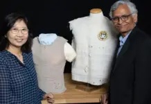 Georgia Tech Named Founding Partner in $480 Million FutureTEX Initiative Smiling woman and man pose beside dress forms displaying fabric samples and a white tuxedo-style jacket with a circular patch badge on the manikin.