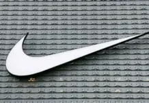 Top 50 Apparel Brands Lose 4% of Combined Brand Value in 2026, Hitting $350.9 Billion Large white Nike swoosh logo mounted on a gray tiled wall backdrop.