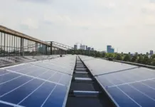 Levi’s and M&S Launch Fashion Renewable Collaborative to Drive Supply Chain Decarbonisation Row of solar panels on a rooftop with a city skyline in the distance.