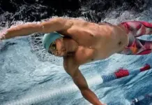 Pentland Brands Strengthens Global Supply Chain Compliance Male swimmer in a turquoise cap and goggles, mid‑stroke in a pool lane during a freestyle race.