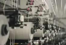 Chinese Textile Giant Shengtai Plans $200M Investment in Morocco Row of textile manufacturing machines with white thread spools feeding along a production line in a factory setting