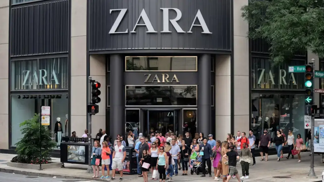 Crowd of shoppers standing outside a Zara store on a city street.