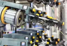 Swedish Textile Technology Companies Drive Innovation Ahead of ITMA Asia 2026 Close-up of an automated industrial knitting machine with multiple needle heads and yellow adjustment knobs in a manufacturing line.
