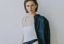 Lenzing and Kaihara Unveil REMOD Collection at Kingpins Amsterdam, Bringing TENCELâ„¢ Lyocell Portfolio to Denim’s Creative Forefront Woman posing in a white tank top with a denim jacket draped over one shoulder, against a light gray background.